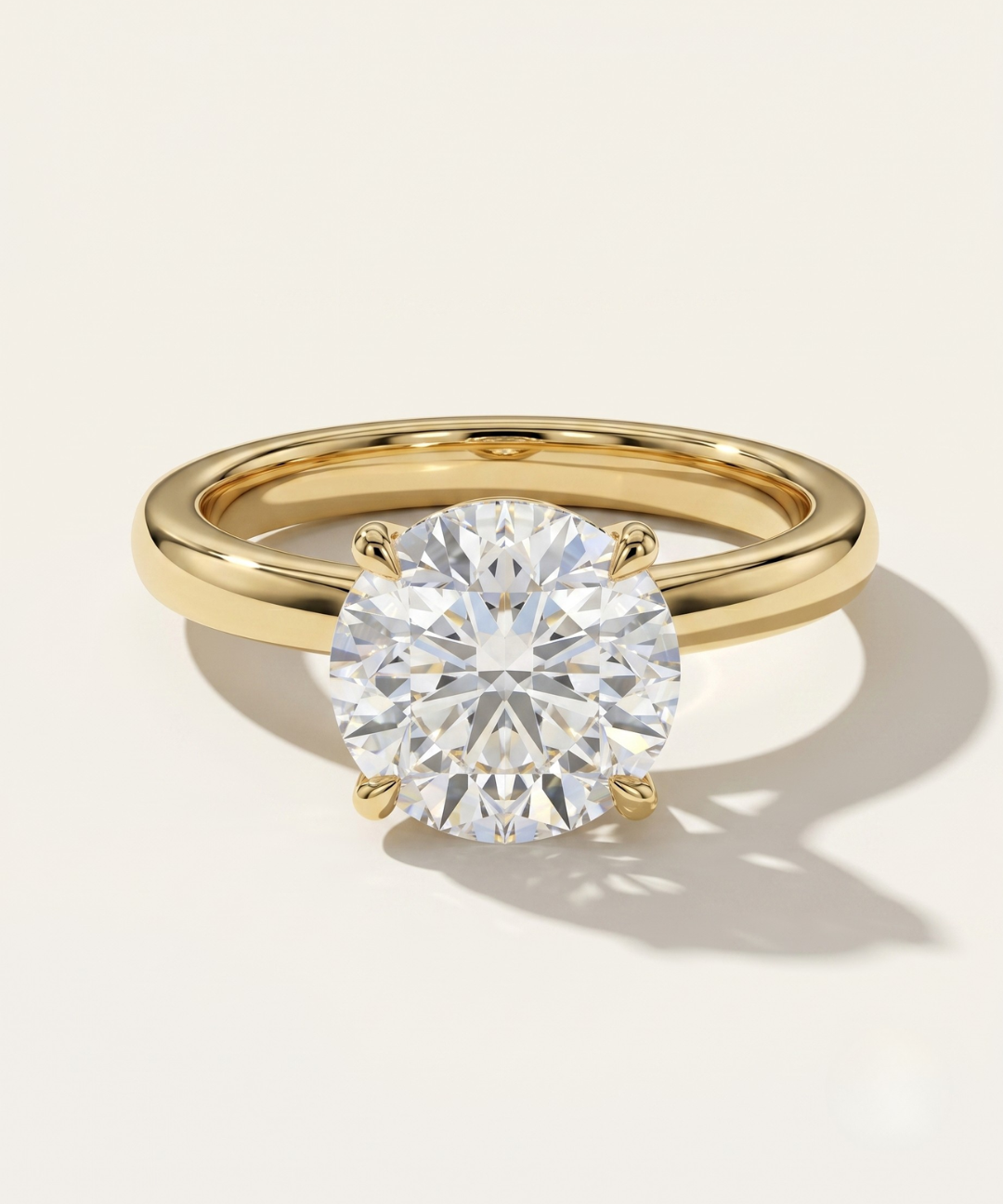 MOHSTEN Uluwatu round diamond solitaire engagement ring in 18ct yellow gold showcasing a premium round brilliant centre stone in a minimalist 4-prong basket setting.