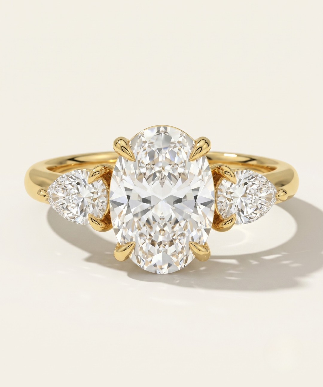 MOHSTEN Valencia oval and pear diamond trilogy engagement ring in 18ct yellow gold showcasing an elongated oval centre diamond paired with two sharp pear-cut side stones.