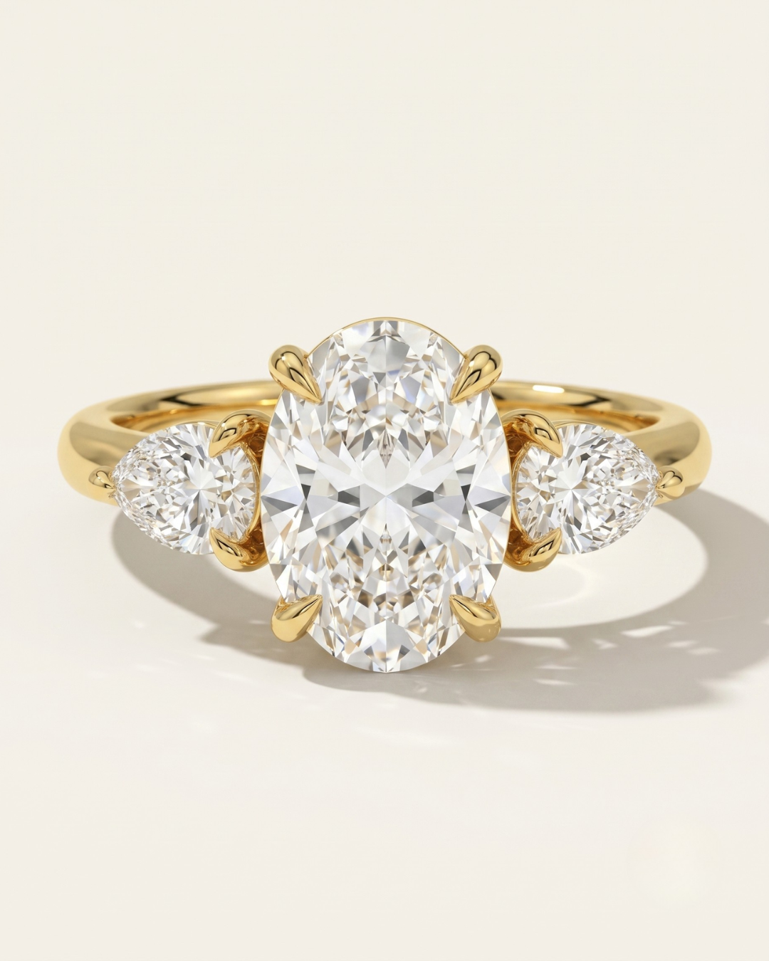 MOHSTEN Valencia oval and pear diamond trilogy engagement ring in 18ct yellow gold showcasing an elongated oval centre diamond paired with two sharp pear-cut side stones.