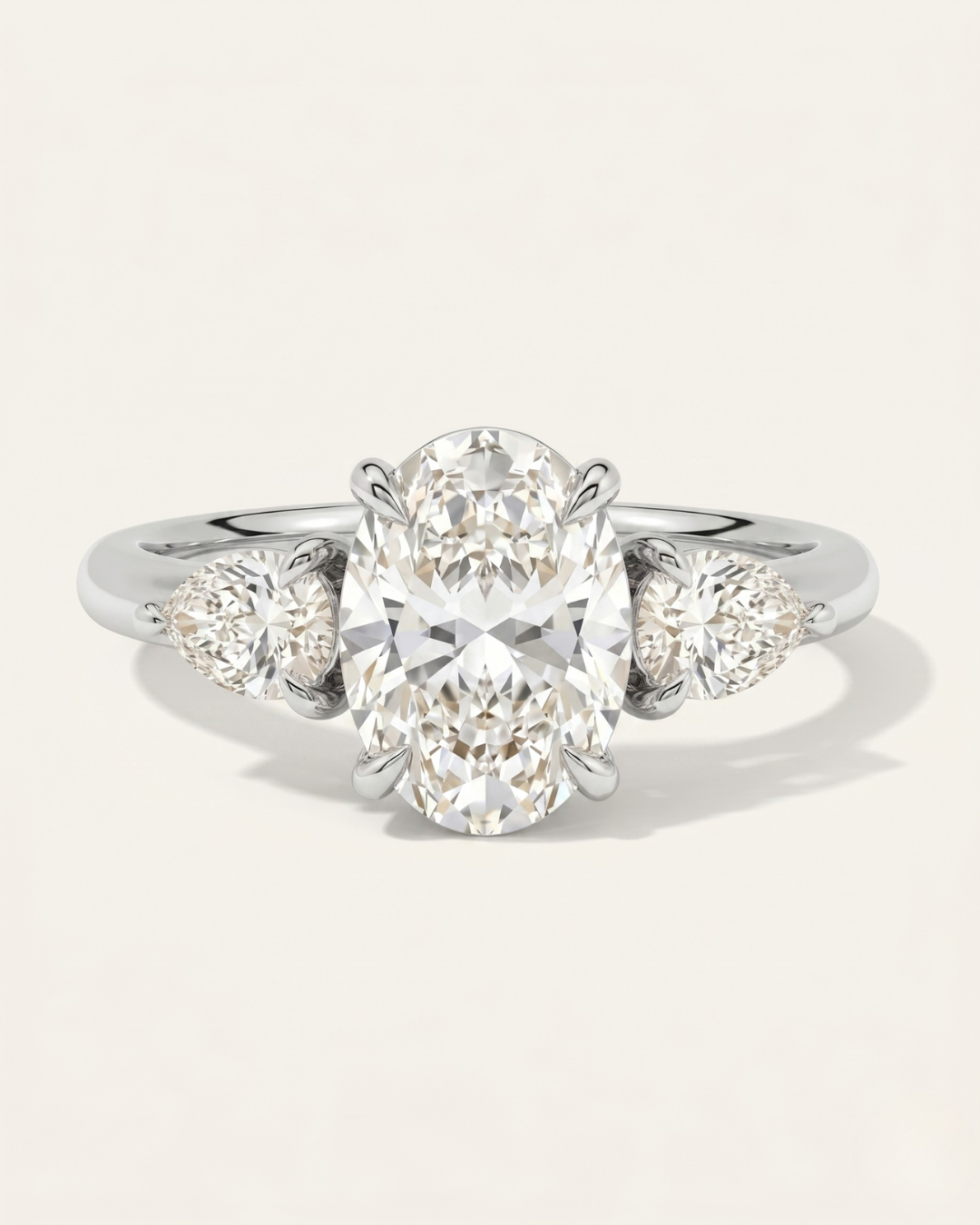 MOHSTEN Valencia oval and pear diamond trilogy engagement ring in polished platinum showcasing an elongated oval centre diamond and two sharp pear-cut side stones.