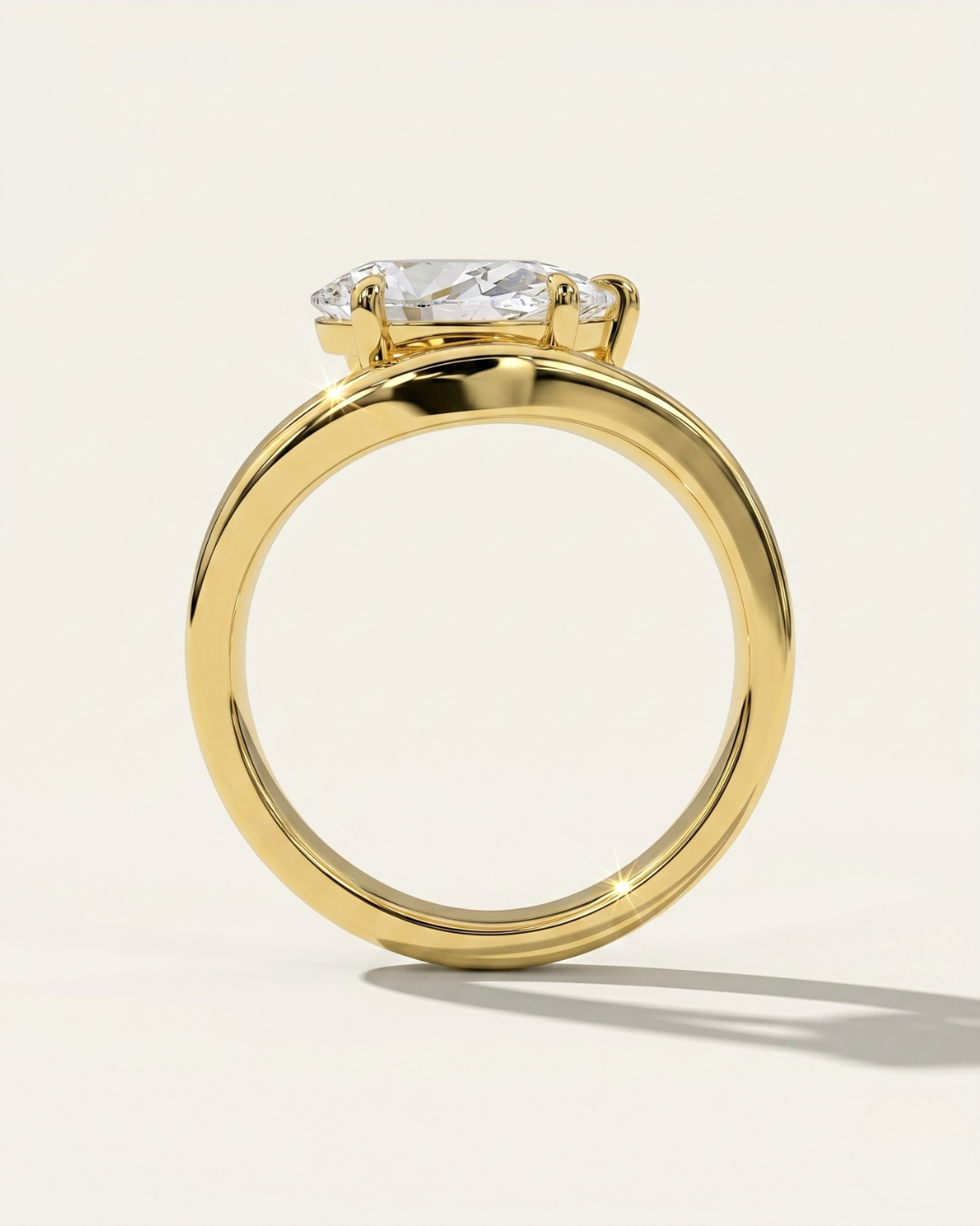 MOHSTEN Venice pear diamond solitaire engagement ring in 18ct yellow gold from a through-finger circular profile view, highlighting the polished round band and the low-profile setting architecture casting a crisp shadow.