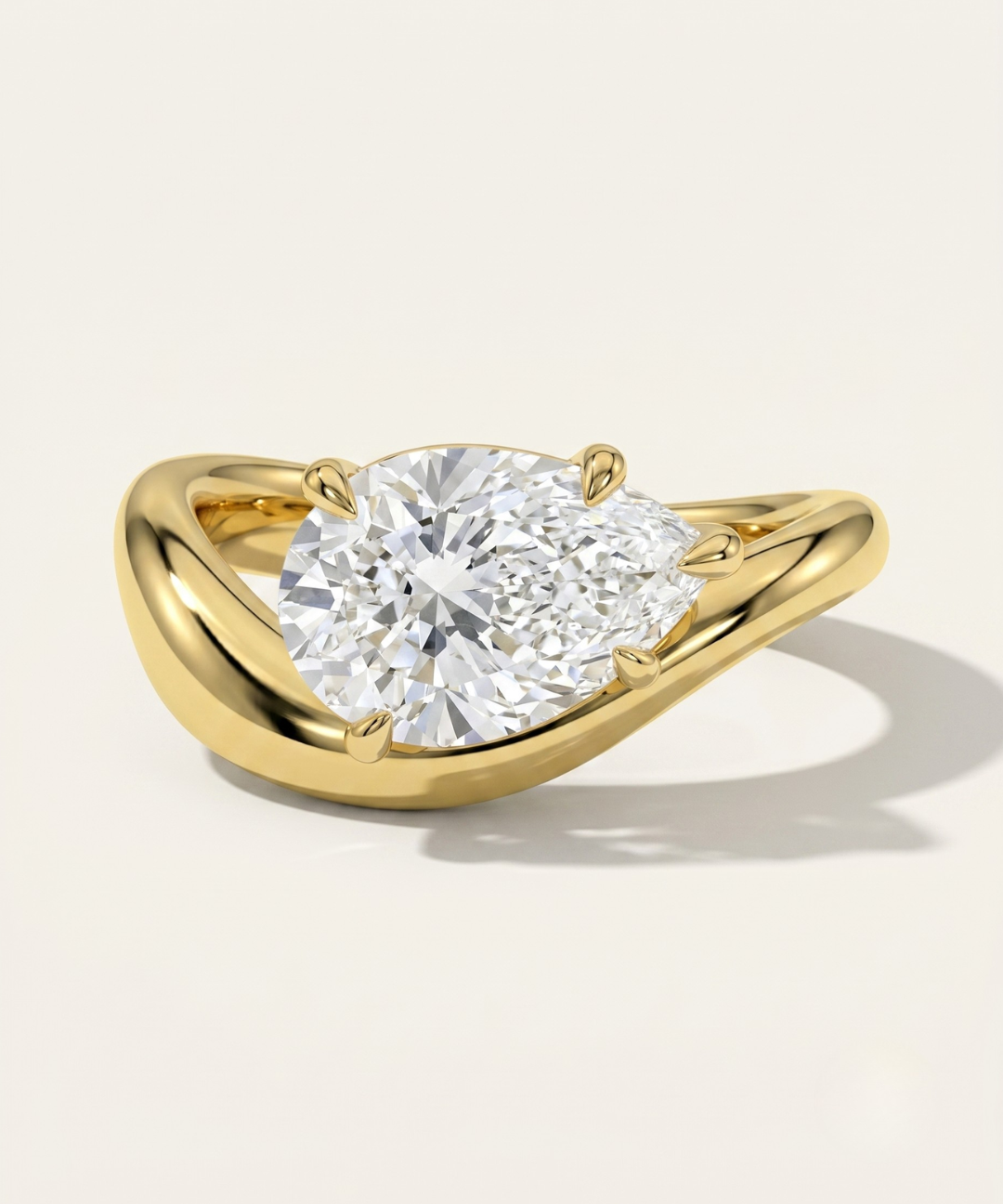 MOHSTEN Venice pear diamond solitaire engagement ring in 18ct yellow gold showcasing an east-west oriented pear diamond on a sleek, organic sweeping band casting a soft shadow on a minimalist studio background.