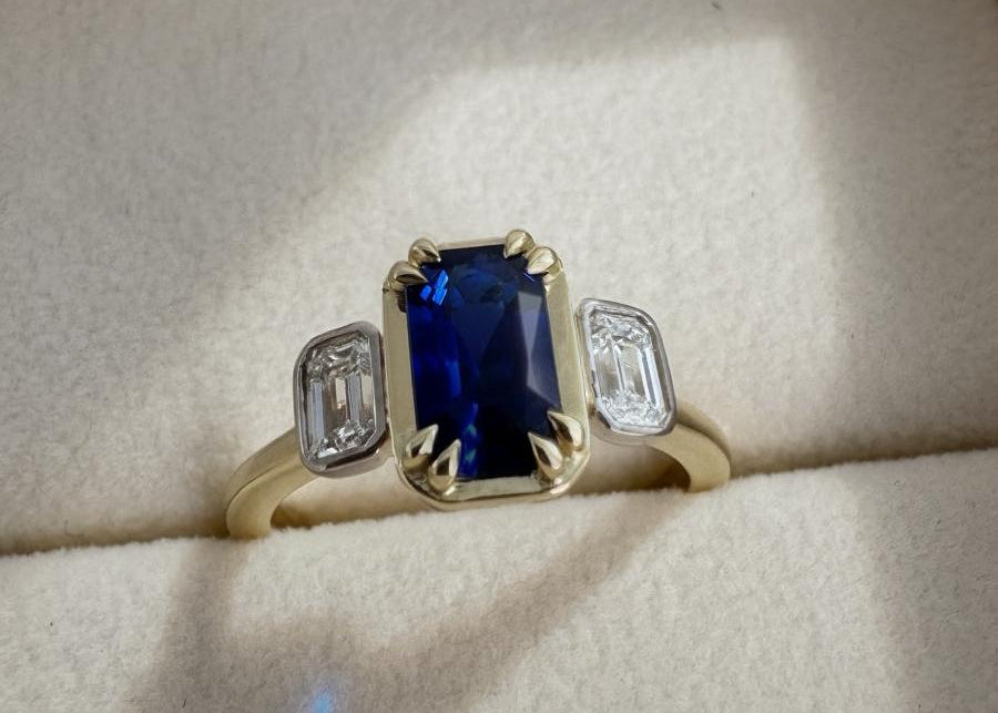 18ct gold ring with a blue sapphire in a light beige box by MOHSTEN