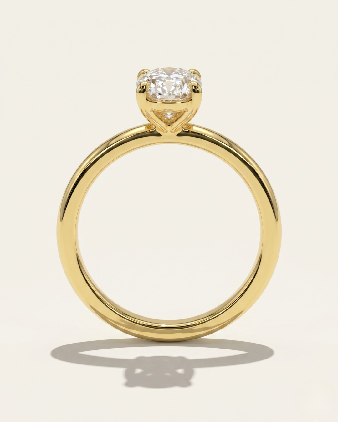 Side profile through-finger view of the MOHSTEN Osaka oval diamond solitaire engagement ring in 18ct yellow gold, highlighting the circular band profile and the minimalist signature 4-prong basket setting casting a shadow.
