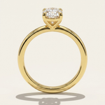 Side profile through-finger view of the MOHSTEN Osaka oval diamond solitaire engagement ring in 18ct yellow gold, highlighting the circular band profile and the minimalist signature 4-prong basket setting casting a shadow.