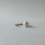 Pearl earring on a light gray background