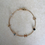 Gold bracelet with small gemstones on a light gray background