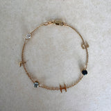 Gold bracelet with small gemstones on a light gray background