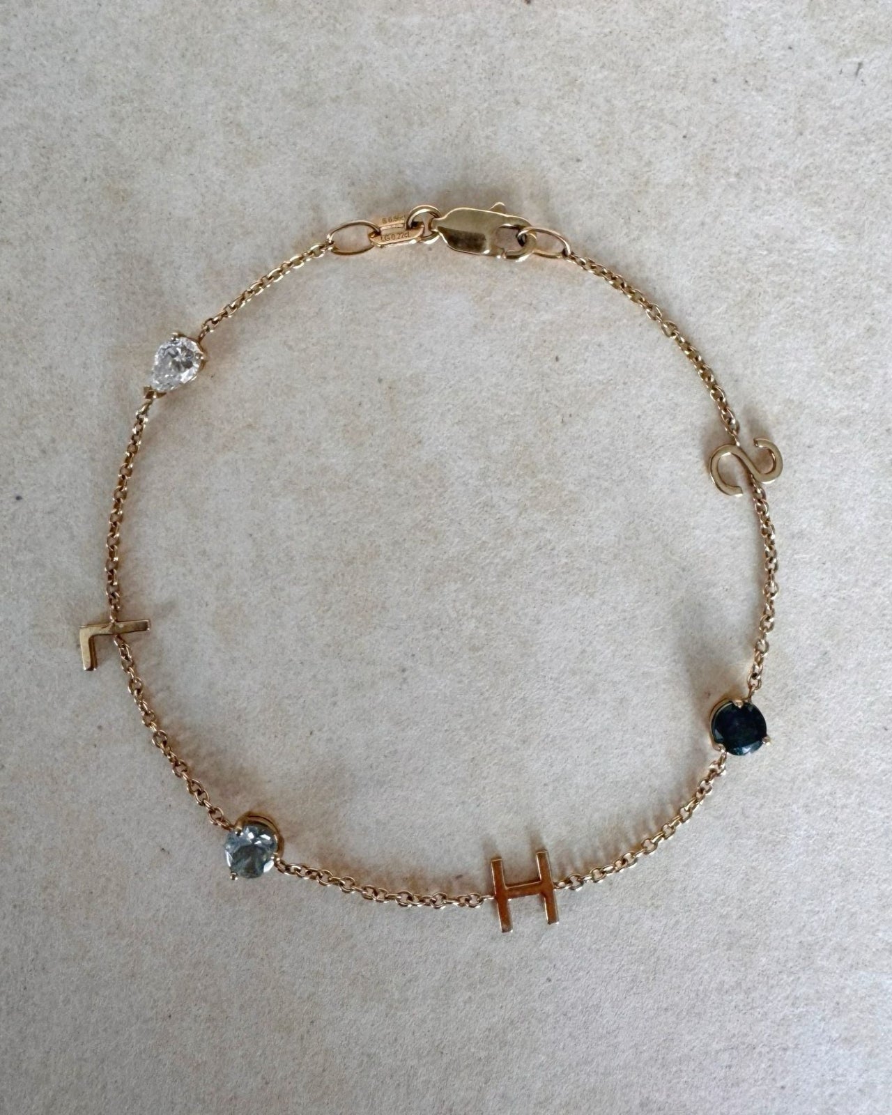 Gold bracelet with small gemstones on a light gray background
