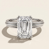 MOHSTEN Brooklyn emerald cut diamond engagement ring in polished platinum displaying the double-claw basket setting and textured band architecture.