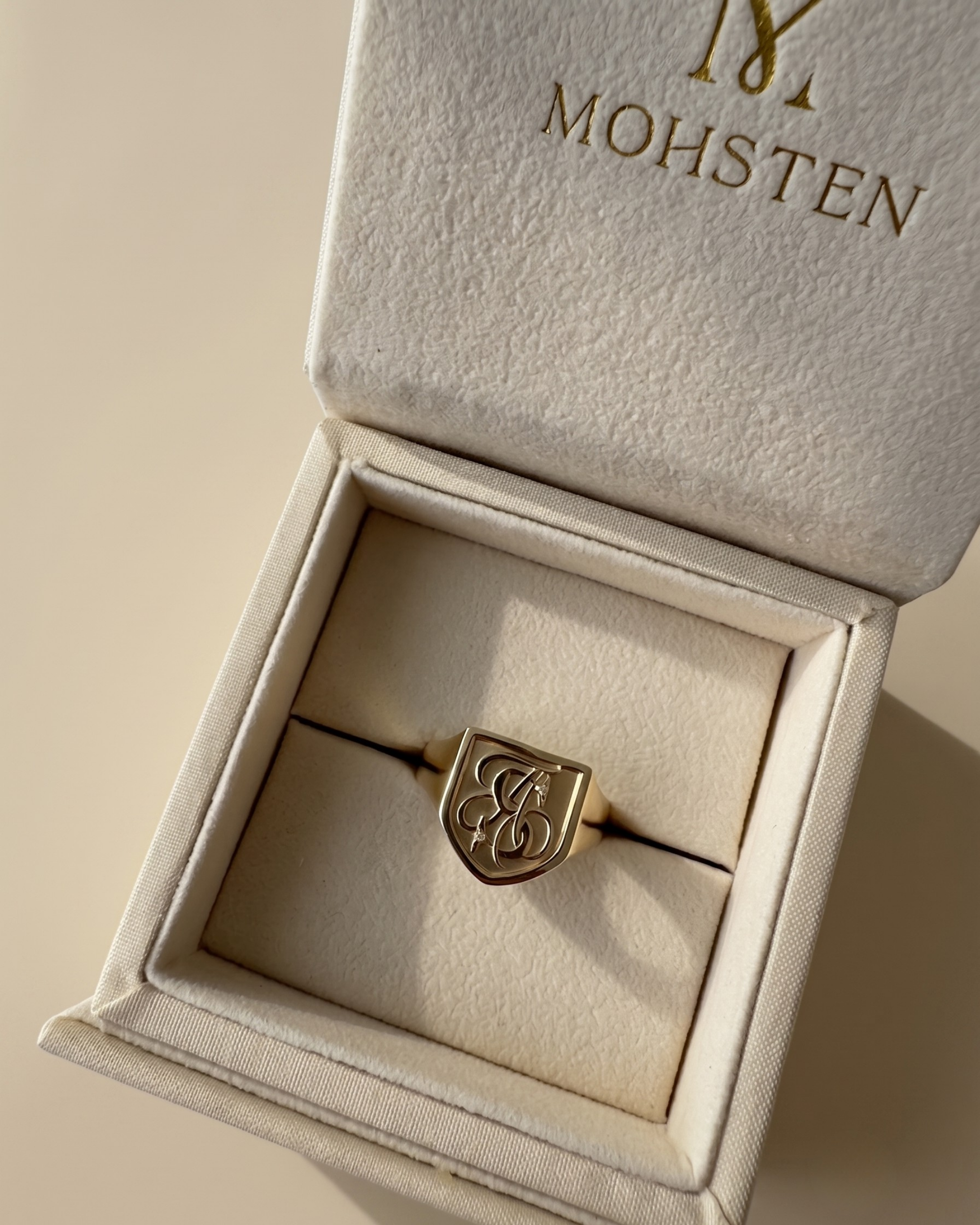 Gold signet ring in a jewellery box with 'MOHSTEN' branding.
