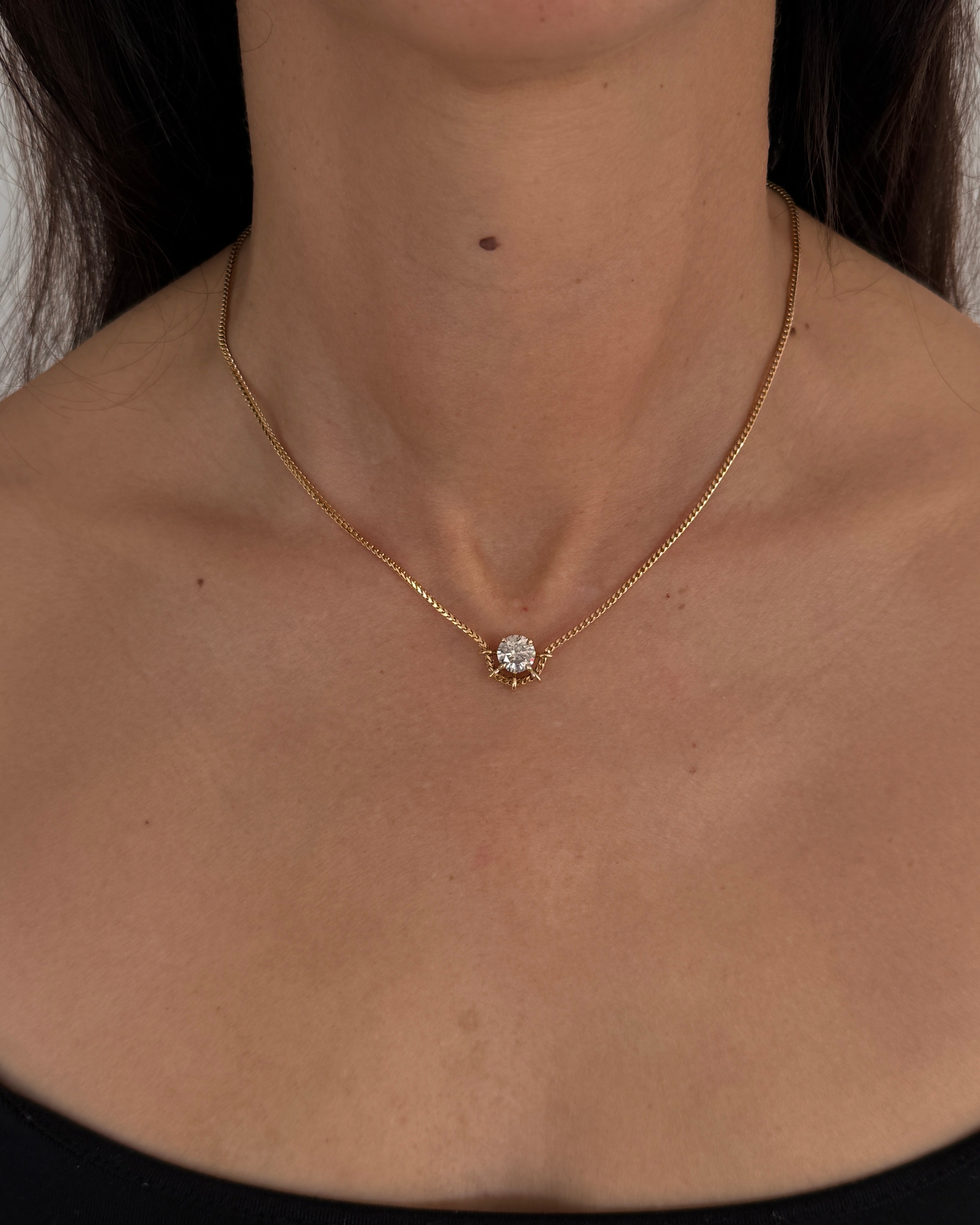 MOHSTEN Solaris Diamond Pendant Necklace in gold, featuring a single round brilliant cut diamond on a fine chain, modelled on a woman's neck.