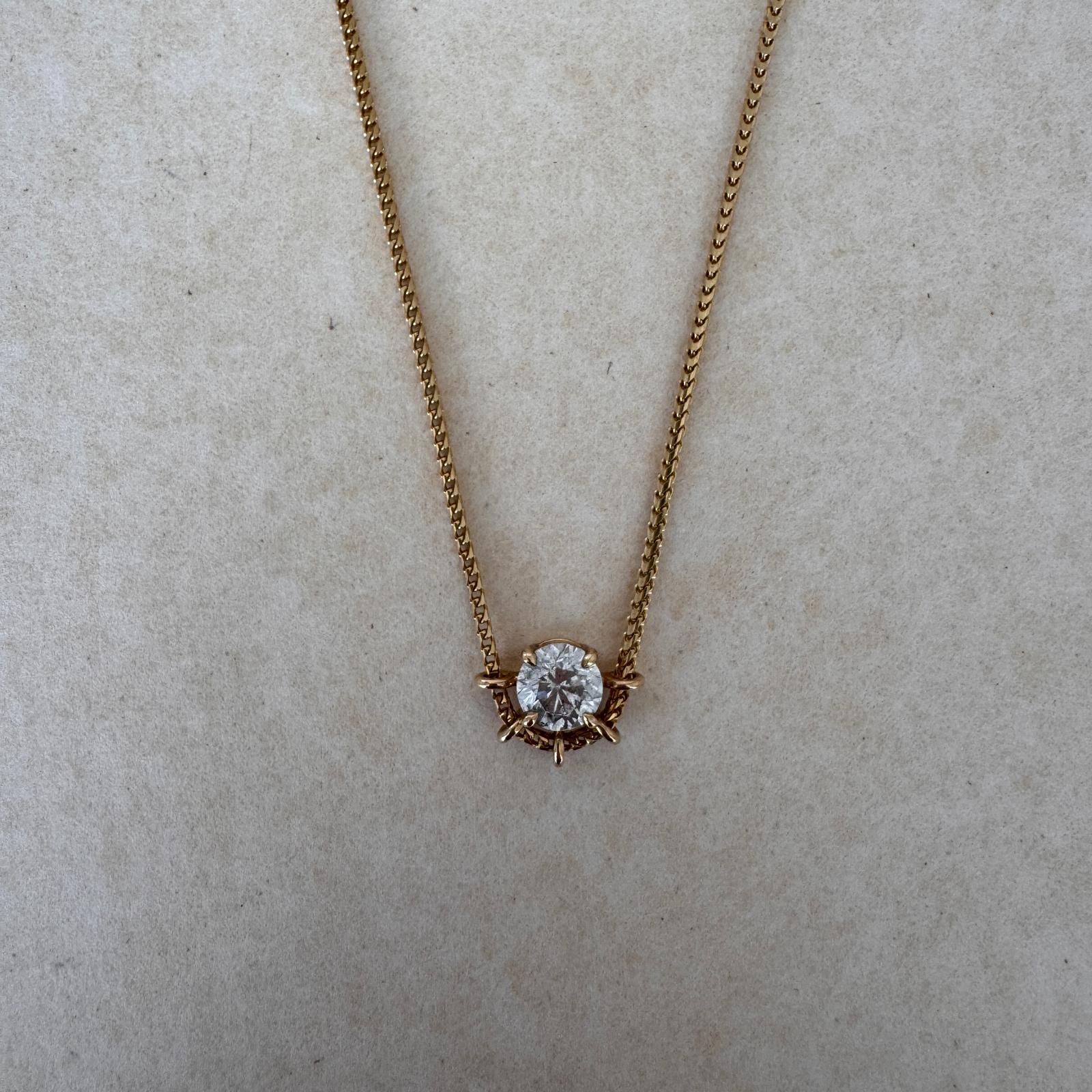 Gold necklace with a diamond pendant on a beige background