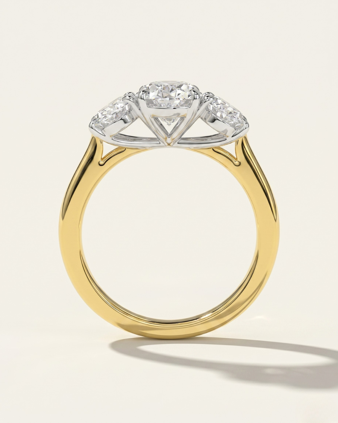 Through-finger view of the MOHSTEN Sydney oval diamond trilogy engagement ring highlighting the structural two-tone contrast between the 18ct yellow gold band and the platinum basket setting.