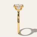 Side profile view of the MOHSTEN Valencia oval and pear diamond trilogy engagement ring in 18ct yellow gold highlighting the fluid band thickness and structural trilogy setting layout.