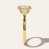Side profile view of the MOHSTEN Valencia oval and pear diamond trilogy engagement ring in 18ct yellow gold highlighting the fluid band thickness and structural trilogy setting layout.