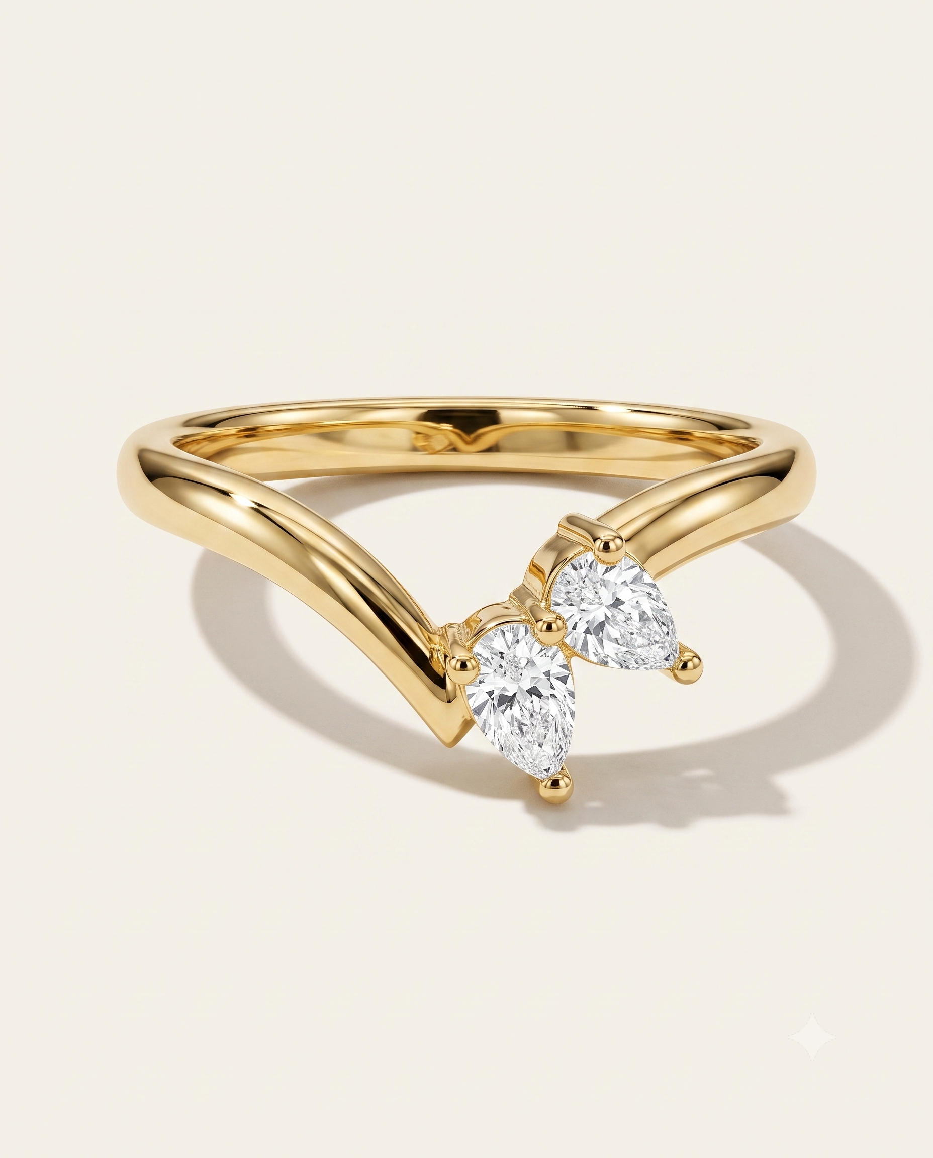 A gold ring with a curved, openwork band and two pear-cut clear gemstones, photographed on a clean off-white background with a soft shadow.